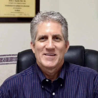 Dr. Steven Augustine is pictured in his office smiling warmly at the viewer